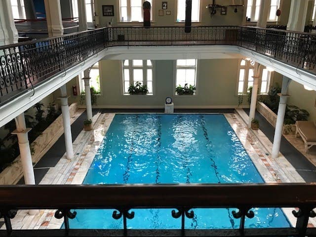 A balcony overlooking an indoor swimming pool at the bottom.