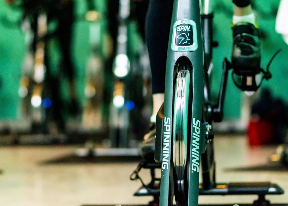Close-up shot of the spinning bike in the gym. The front part has a sticker on it that reads “SPINNING.”