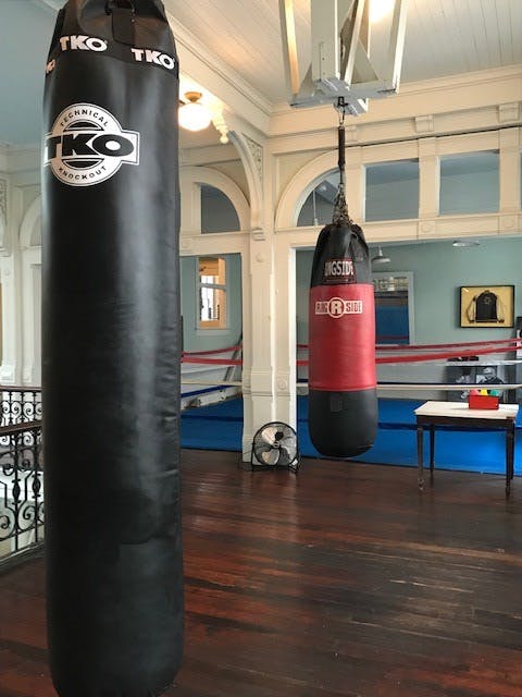 Two punching bags hanging from the ceiling. The one at the front is black, and the one at the back is red.