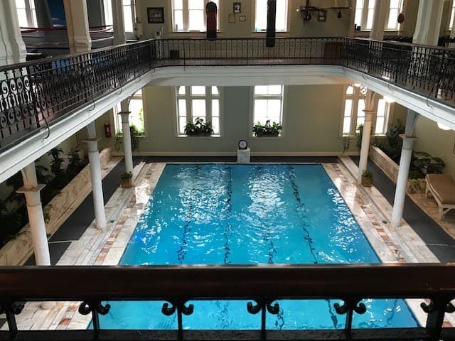 A balcony overlooking an indoor swimming pool at the bottom.